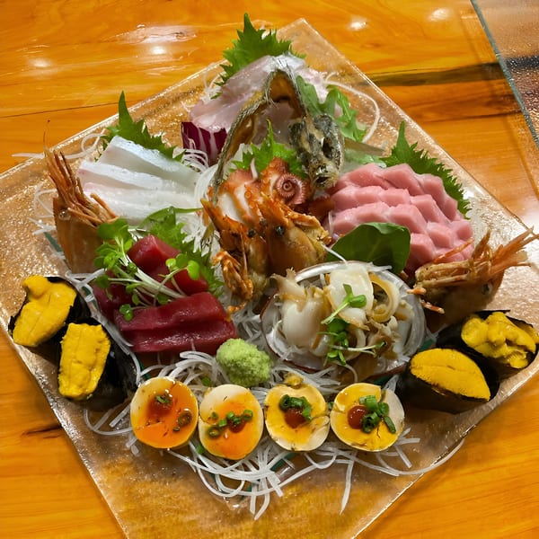 A large platter of Kiku Sushi's sashimi, including tuna, octopus, shrimp, uni, and quail eggs.