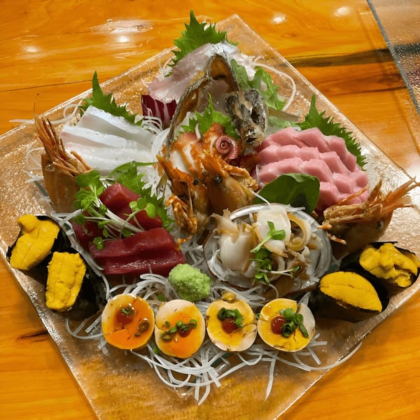 A large platter of Kiku Sushi & Vegetarian's sashimi, uni, shrimp, and soft-boiled eggs.
