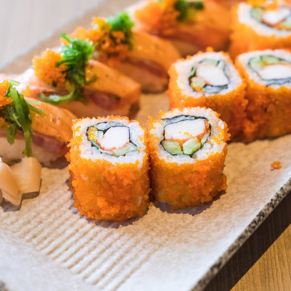 A plate of Kiku Sushi & Vegetarian's California rolls and salmon nigiri with roe and seaweed.